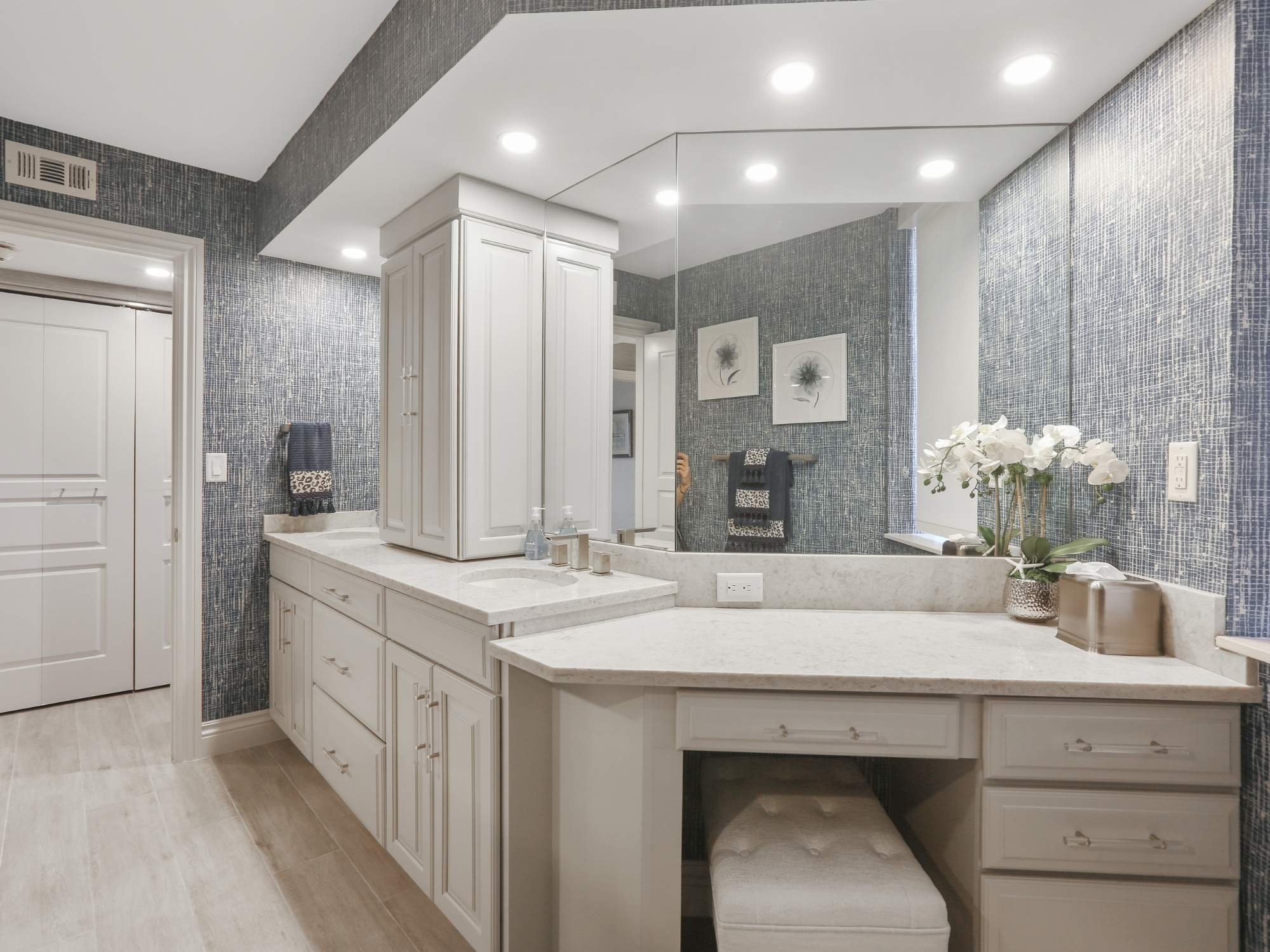 Remodeled bathroom with white cabinetry, dual vanities, blue textured walls, and a large mirror in Southwest Florida.