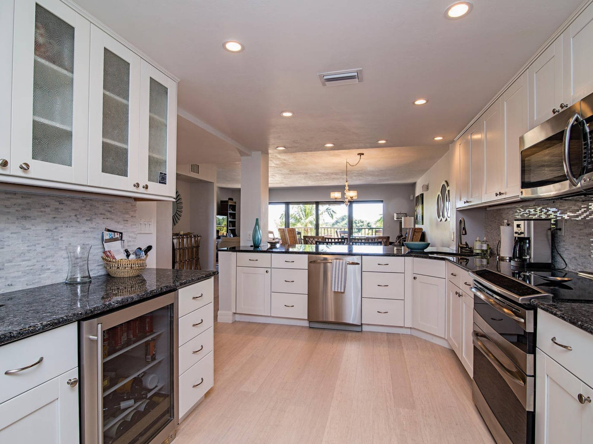 Kitchen with white cabinetry, dark stone countertops, stainless steel appliances, and an open layout in Southwest Florida.